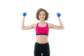 Curly young woman with dumbbells in hands, standing on a white background. Happy girl is engaged in fitness.