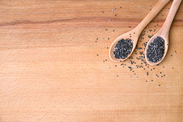 Chia seeds in wooden spoons on a wood background. Top view. Slimming and diet concept. Place for text