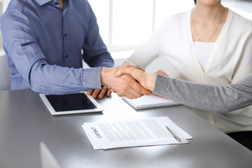 Group of business people shaking hands after discussing questions at meeting in modern office. Handshake close-up. Teamwork, partnership and agreement in business concept