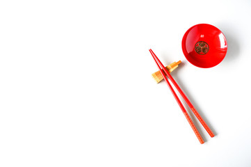 Wooden chopsticks and red cups on a white table top view