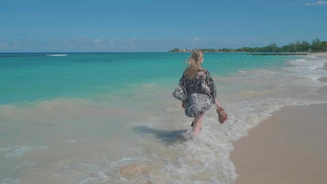 Blonde female walking along beautiful caribbean beach in Jamaica