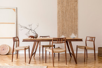 Stylish and beige interior of dining room with design wooden table and chairs, vase with flowers,...