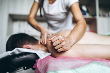 Fototapeta na wymiar Female masseuse gives back massage to man who is lying on massage couch