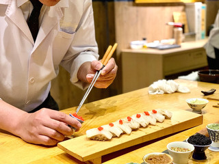 	 Closeup of chef hands preparing japanese food. Japanese Omakase Chef making sushi at restaurant. chef serving traditional japanese sushi with gold served on a stone plate.
