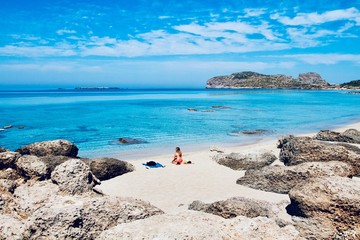 Beautiful girl looking the transparent and turquoise sea of Falassarna beach, Crete, Greece 