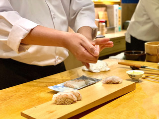 	 Closeup of chef hands preparing japanese food. Japanese Omakase Chef making sushi at restaurant. chef serving traditional japanese sushi with gold served on a stone plate.