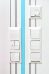 Wall mounted light switches, roller shutter control switch for closing windows, electrical outlet and temperature controller close-up