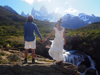 The bride and groom holding hands on the banks of a stream and looking out over Mount Fitz Roy, Mountain wedding, Forest wedding, Los Glaciares National Park near El Chalten, Patagonia, Argentina