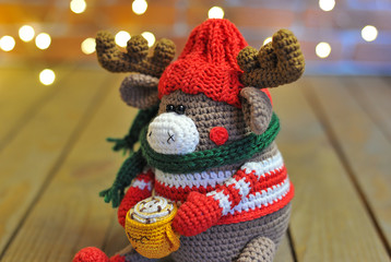 knitted elk. cute moose. toy against the background of a New Year's garland