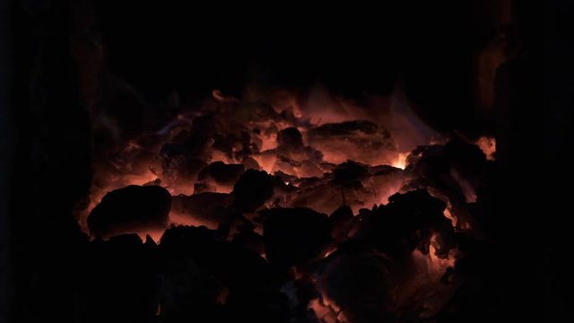 Slow motion. Burning coal in the stove. Live coal, embers, glowing coals, abstract background.
