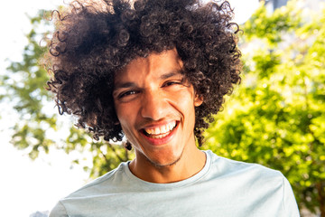 young North African man with afro hair laughing outside