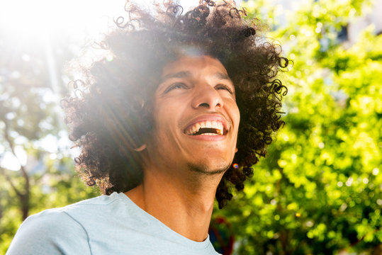 Close up handsome young North African man with afro hair laughing outside