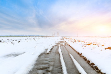 Muddy dirt road covered with snow in the countryside
