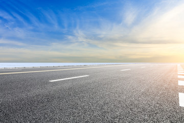 Fototapeta premium Country road and farmland snow scene at sunset