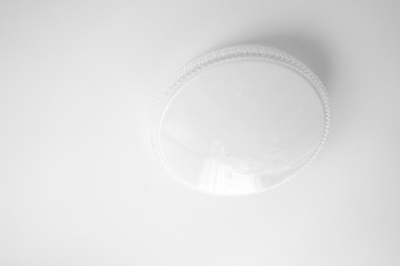 Ordinary round white chandelier on a white ceiling background, close-up