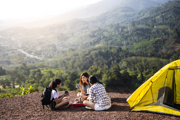Two asian female hikers sit and clinking glasses by tent. - 303335658