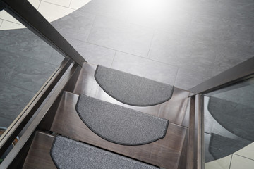 Steps of dark wooden staircase with anti-slip mat