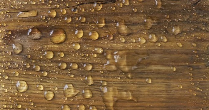 Strong wind blows away raindrops from a brown wooden surface. Classic natural combination of water and wood.