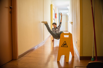 Man slips on wet floor. Wet floor danger sign in the foreground. Concept of danger slipping