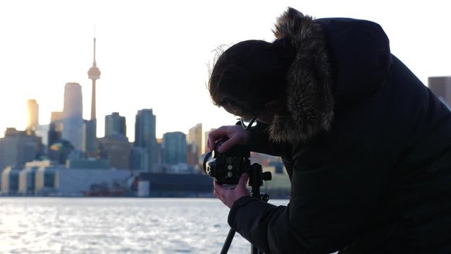 Photographer with tripod and dslr taking photos of Toronto cityscape sunset 3