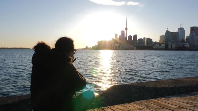 Photographer sitting down taking photos with dslr of Toronto cityscape