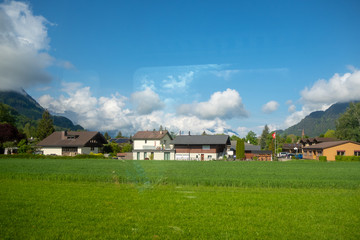 Fototapeta na wymiar Beautiful view of small village and field in rural area of switzerland on blue sky with clouds background and copy space