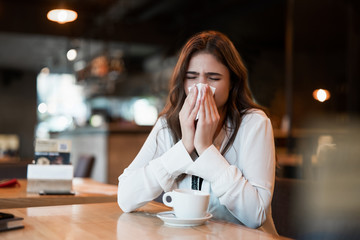 young beautiful woman in white stylish blouse feeling sick bowing out her nose after hard workday...