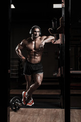 Fototapeta na wymiar Muscular athletic bodybuilder fitness model rest after training with barbell in gym. Concept sport photo of exercises in gym