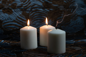 White burning candles on dark background