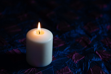 One white candle on dark background