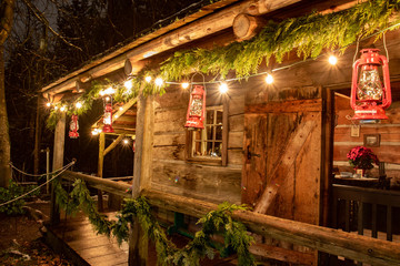 Fototapeta na wymiar Tiny and Cozy house Cabin Exterior with Christmas lights. Ideal picture that brings up holiday spirit.