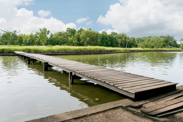 Naklejka premium Wood bridge on the sea which has walk way for travel tourism with tropical forest island and sunshine with sky beautiful background for holiday destination for tourists.