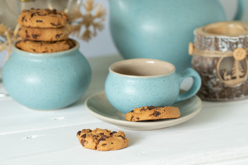 Coffee with chocolate cookies in a blue ceramic cup on the background of Christmas accessories