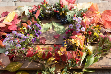 On a wooden background, a bright autumn wreath of rose hips, autumn flowers and autumn leaves.