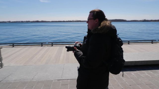 Photographer walking along waterfront boardwalk taking photos 2