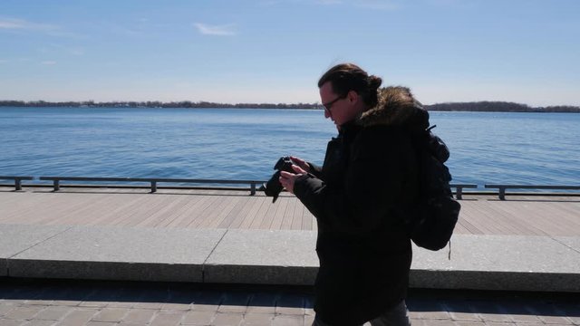 Photographer walking along waterfront boardwalk taking photos 1