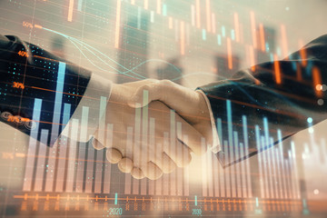 Double exposure of financial graph on cityscape background with two businessman handshake. Concept of stock market deal