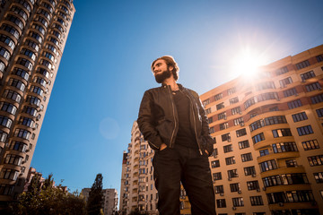 Low angle shot of young guy, standing in the urban block.