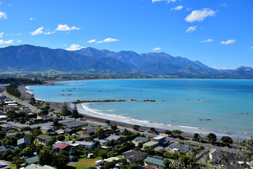 New Zealand landscape with the town Kaikoura, mountains and an ocean with turquoise water.
