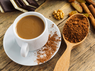 Coffee in a white Cup, sweets and scattered cinnamon on a wooden table
