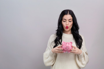 Young woman with a piggy bank on a gray background