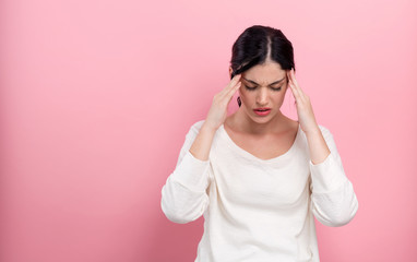 Young woman feeling stressed on a pink background