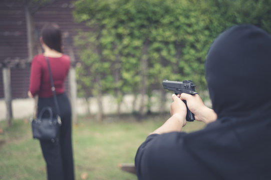 bandit using black gun point to backward of woman, concept of criminal, bandit, gangster, mafia