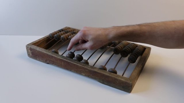 hand counts on wooden old abacus or wooden bills on a white background. Antique concept.