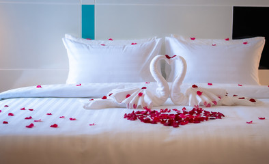Sweet room in holiday, Swan towel decoration on bed with white pillow in bedroom interior.