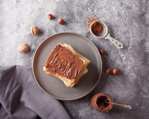 Bread toast with chocolate cream butter, jar of chocolate cream on the concrete background