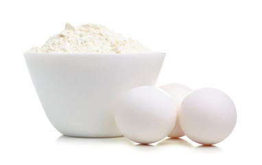 White bowl with flour and eggs on white background isolation