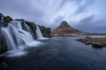 Fototapeta na wymiar Famous mountain with waterfalls in Iceland, kirkjufell, winter in Iceland, ice and snow, reflections, yellow grass, nature, icelandic famous landscape