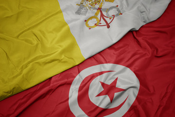 waving colorful flag of tunisia and national flag of vatican city.