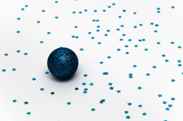 Christmas minimal composition. Blue Christmas ball on a white background adorned with blue stars. Christmas, winter, New year concept. Festive background. Copy space